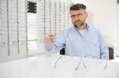 Gözlük kontrolü, kıdemli vizyon ve sağlık için bir optometri kliniğinde yaşlı bir adam. Mutluluk, gülümseme ve lens, çerçeve ve gözlük seçimi ile reçeteli ilaç almak için bir mağazada