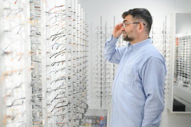 Son sınıf öğrencisi optik mağazada gözlük seçiyor.