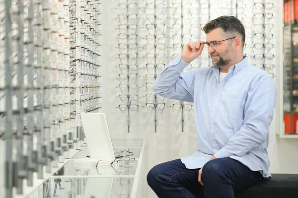 光学店で眼鏡を選ぶ男性客は — ストック写真