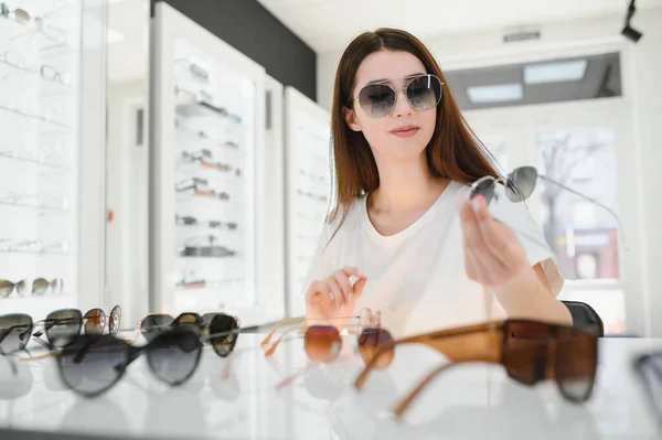 Mladá Žena Vybere Sluneční Brýle Obchodě Optikou — Stock fotografie
