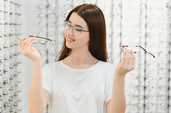 Young Woman with Eyeglasses in Optical Store - Beautiful girl wearing glasses in optician shop.