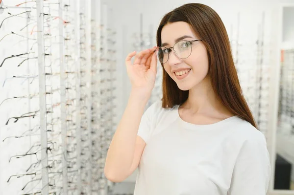 Young Woman with Eyeglasses in Optical Store - Beautiful girl wearing glasses in optician shop.