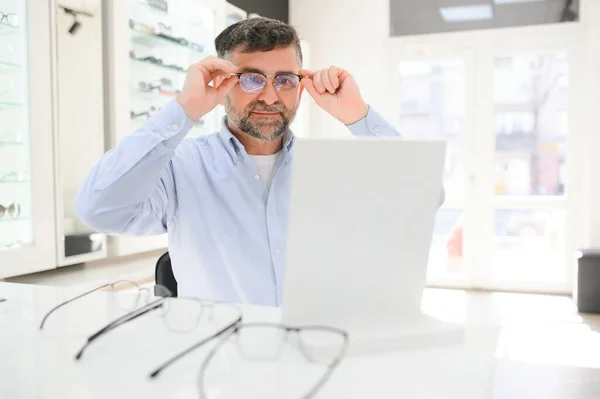 光学店で眼鏡を選ぶ男性客は — ストック写真