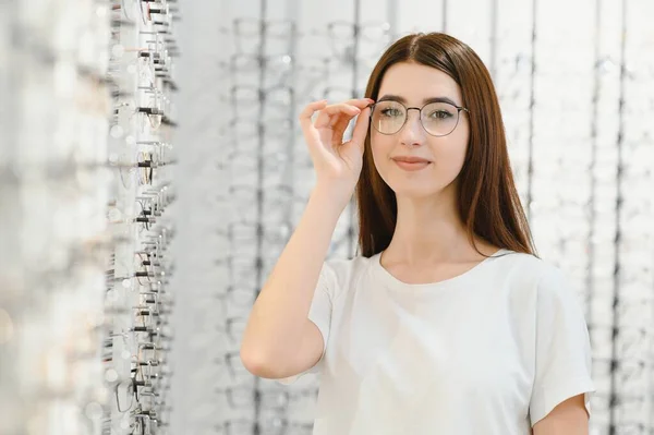 stock image Young Woman with Eyeglasses in Optical Store - Beautiful girl wearing glasses in optician shop.