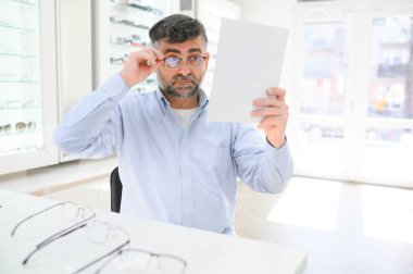 Son sınıf öğrencisi optik mağazada gözlük seçiyor. Mükemmel olana karar vermek için gözlük çerçevesi dene..