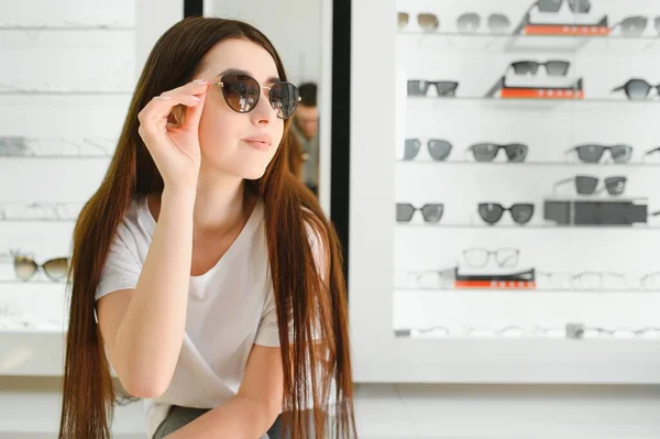 Młoda Kobieta Wybiera Okulary Przeciwsłoneczne Dla Siebie Sklepie Optycznym — Zdjęcie stockowe