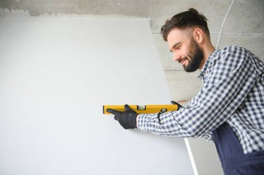 İnşaat alanında ruh seviyesiyle poz veren inşaatçı.