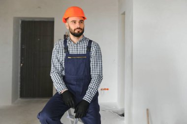 Gri beton duvarın arkasında gülen inşaat işçisi. Yenileme. metin için yer.