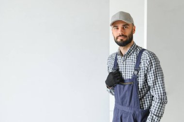 Mavi sakallı yakışıklı tamircinin portresi. Gömleği kollarını kavuşturmuş, kameraya bakıyor..