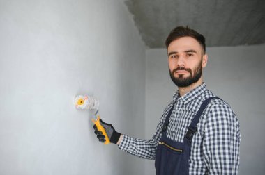 Mavi sakallı yakışıklı tamircinin portresi. Gömleği kollarını kavuşturmuş, kameraya bakıyor..