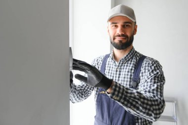 Mavi üniformalı sıva duvarları kapalı kapılar ardında yapıştırıyor..