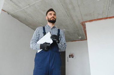 Gri beton duvarın arkasında gülen inşaat işçisi. Yenileme. metin için yer.