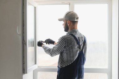 İnşaat işçisi eve pencere kuruyor.