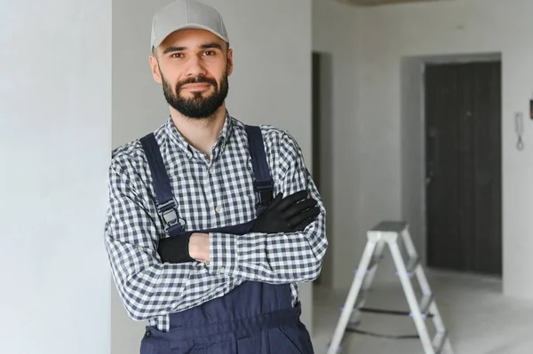 stock image smiling repairman standing near stepladder and looking at camera.