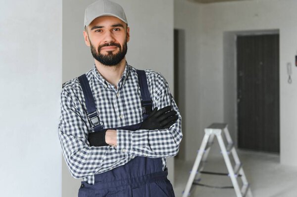 smiling repairman standing near stepladder and looking at camera.