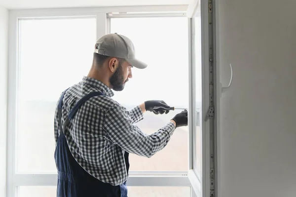 작업복을 근로자가 거실에 플라스틱 창문을 설치하거나 조정하는 — 스톡 사진