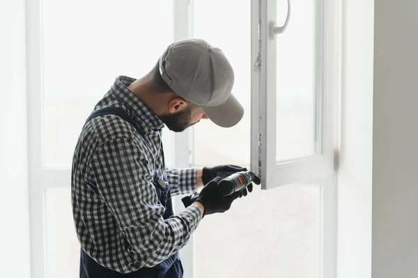 Robotnik Kombinezonach Instalujący Lub Regulujący Okna Tworzywa Sztucznego Salonie Domu — Zdjęcie stockowe