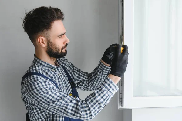 작업복을 근로자가 거실에 플라스틱 창문을 설치하거나 조정하는 — 스톡 사진