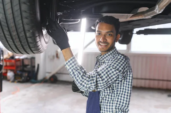 印度汽车技师站在加油站工作 汽车专家检查吊车 身穿蓝色机修工制服的专业修理工 — 图库照片