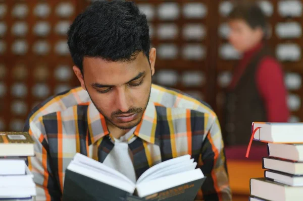 课间休息时 带着背包 学习用品站在大学图书馆或书店的书架上的快乐的国际印度男生的画像 教育概念 — 图库照片