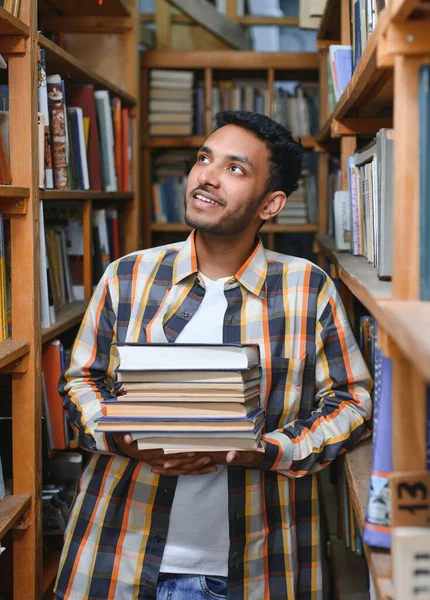 バックパック付きの明るい男性留学生の肖像画 授業の合間に大学図書館や書店の本棚の近くに立っているアクセサリーを学ぶ 教育理念 — ストック写真