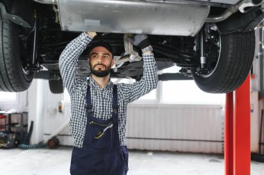 Mavi üniformalı yetişkin adam otomobil salonunda çalışıyor.