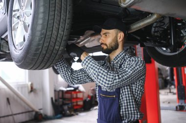 Otomobil tamircisinde çalışan bir tamirci..