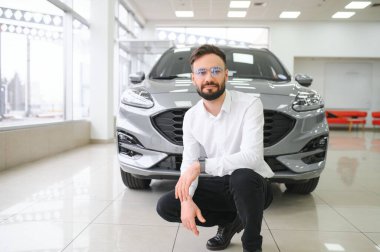 Kendine güvenen müşteri erkek alıcı beyaz gömlek giyer. Otomobili seçer. Galerideki araba galerisinde yeni otomobil almak ister.