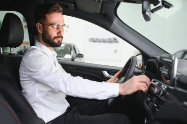 Bir adam araba galerisinde bir arabayı inceler..