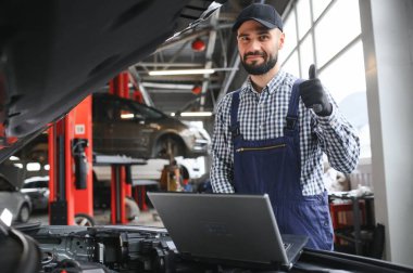 Mavi üniformalı yetişkin adam otomobil salonunda çalışıyor.