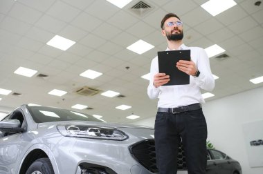 Gülümseyen, dost canlısı araba satıcısı araba kuaföründe duruyor.