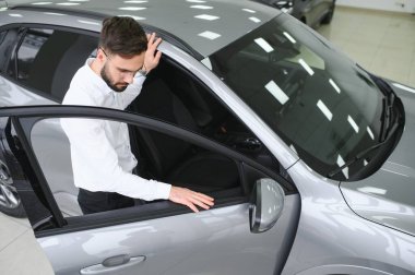 Happy caucasian man in formal wear getting inside luxury modern car for testing interior before purchase. Concept of dealership, selling and purchase.