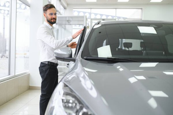 a man examines a car in a car dealership.