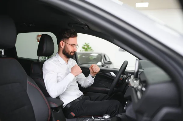 a man examines a car in a car dealership.