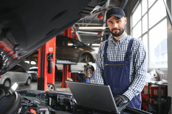 Smiling mechanic using a laptop pc at the repair garage