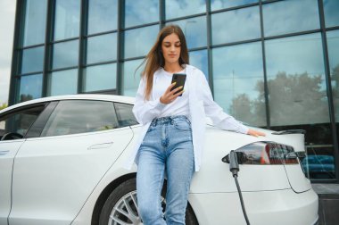 Kız elektrik benzinliğinde elektro araba şarj ediyor..