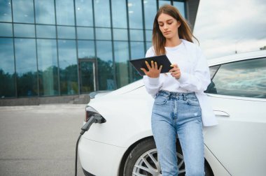 Kız elektrik benzinliğinde elektro araba şarj ediyor..