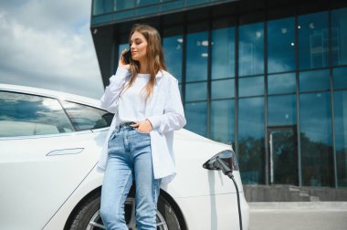 Kız elektrik benzinliğinde elektro araba şarj ediyor..