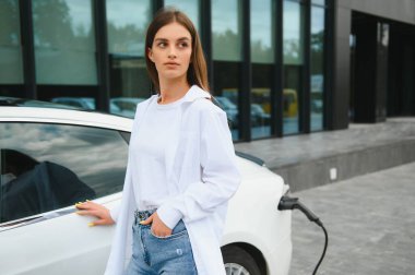 Kız elektrik benzinliğinde elektro araba şarj ediyor..