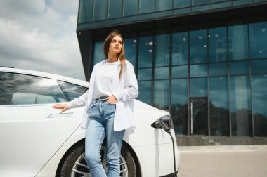 Kız elektrik benzinliğinde elektro araba şarj ediyor..