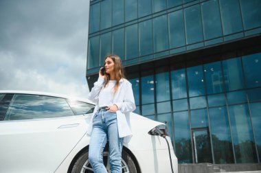 Kız elektrik benzinliğinde elektro araba şarj ediyor..