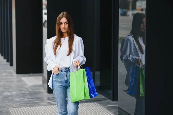 拿着奢侈品牌购物袋的女人走在购物中心附近 — 图库照片