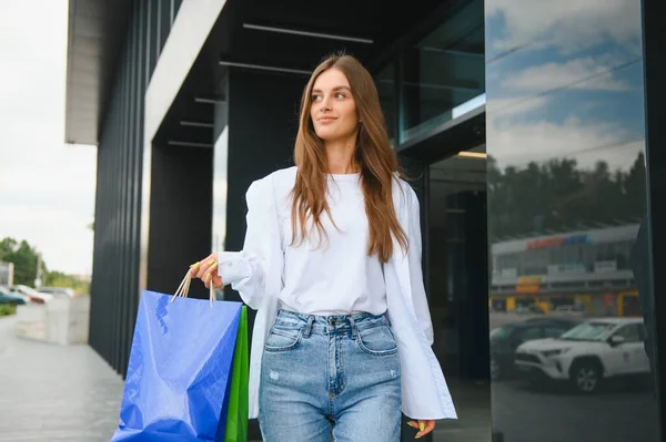 拿着奢侈品牌购物袋的女人走在购物中心附近 — 图库照片
