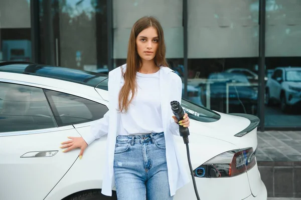 stock image Woman near electric car. Vehicle charged at the charging station