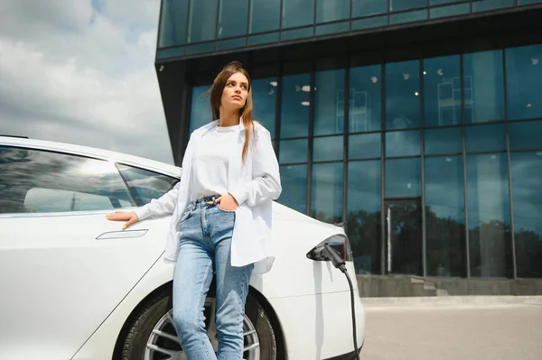 Kız elektrik benzinliğinde elektro araba şarj ediyor..