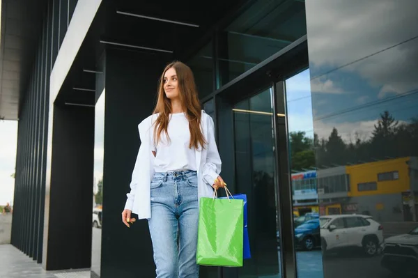 黒金曜日のショッピングセンターの近くにショッピングバッグで立っているファッショナブルな美しい幸せな女性 — ストック写真