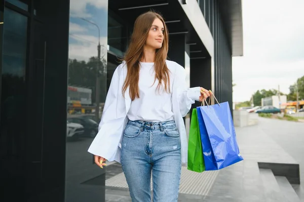 黒金曜日のショッピングセンターの近くにショッピングバッグで立っているファッショナブルな美しい幸せな女性 — ストック写真