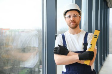 Worker using bubble level after plastic window installation indoors.