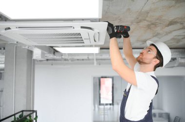 Yakışıklı genç elektrikçi bir müşteri evine klima kuruyor.