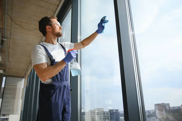 An employee of a professional cleaning service washes the glass of the windows of the building. Showcase cleaning for shops and businesses